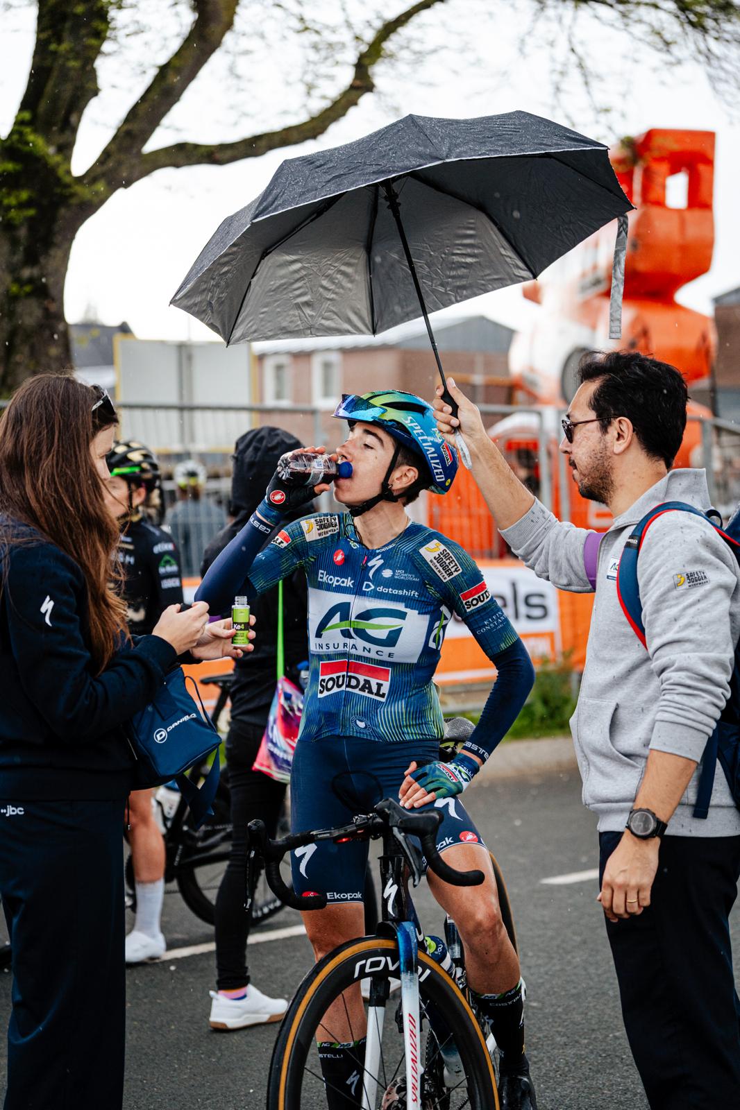 Renster drinkt water na de finish in de regen, paraplu boven haar hoofd